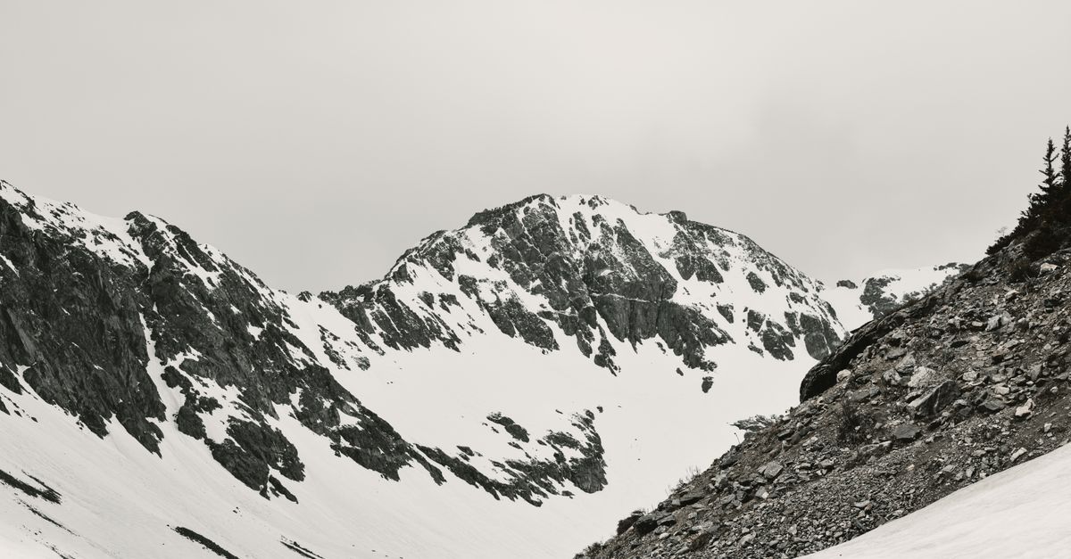 A serene black and white panorama of snow-covered rocky mountain slopes in Colorado.